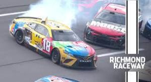 Kyle Busch in yellow number 18 NASCAR car is wrecked by Ross Chastain in red number 1 NASCAR car