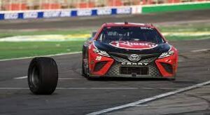 A loose tire rolls away from Christopher Bell's red and black NASCAR car